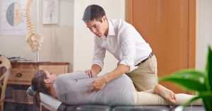 Person lying on examination table with chiropractor twisting leg across their body