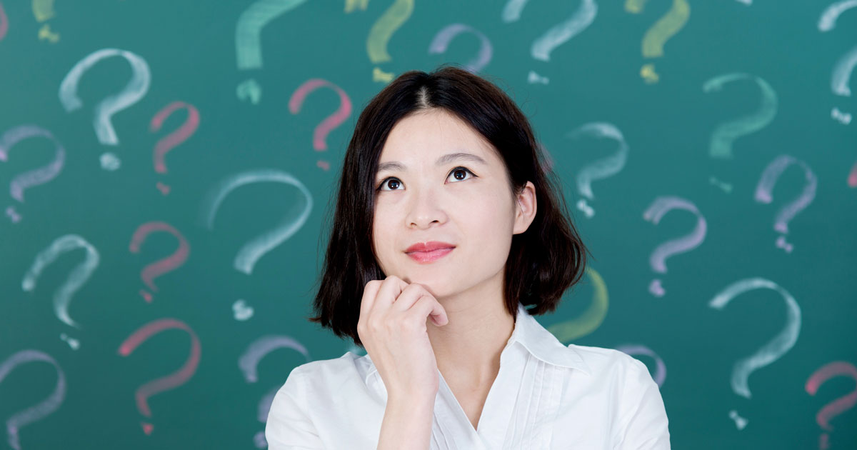 Woman in front of blackboard with question marks on it
