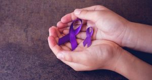 Hands holding two purple ribbons